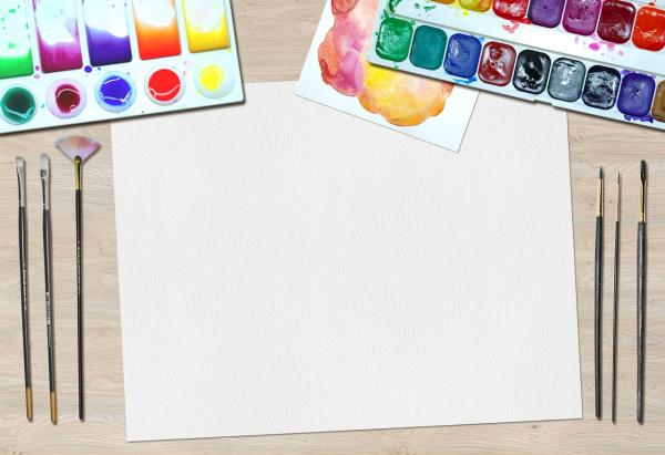 a blank piece of paper surrounded by paints and brushes
